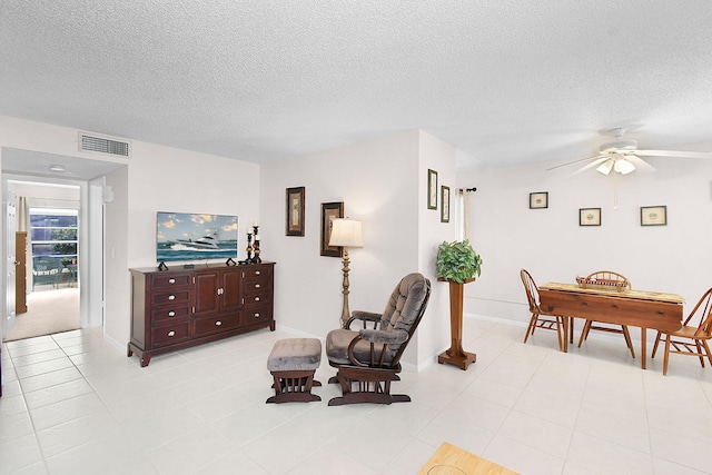 sitting room featuring ceiling fan, light tile patterned floors, and a textured ceiling