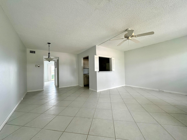 unfurnished room with ceiling fan, light tile patterned flooring, and a textured ceiling