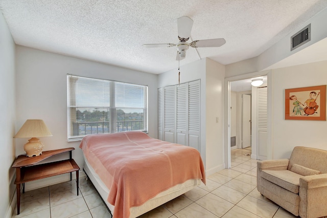 bedroom featuring ceiling fan, a textured ceiling, a closet, and light tile patterned floors