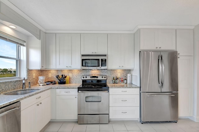 kitchen with sink, backsplash, white cabinets, light stone counters, and stainless steel appliances