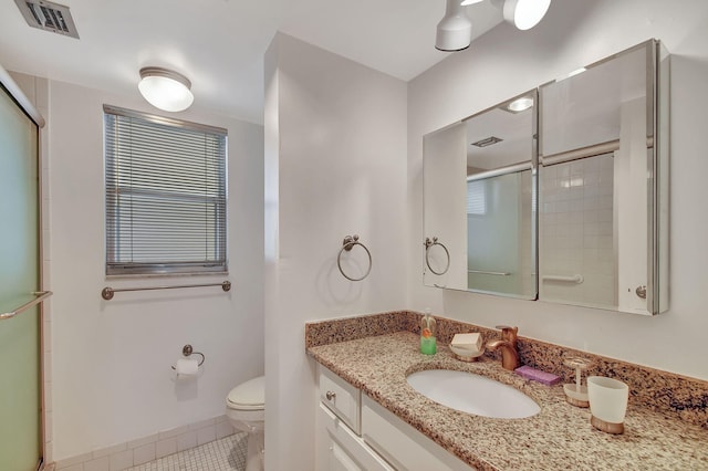 bathroom featuring walk in shower, vanity, toilet, and tile patterned flooring