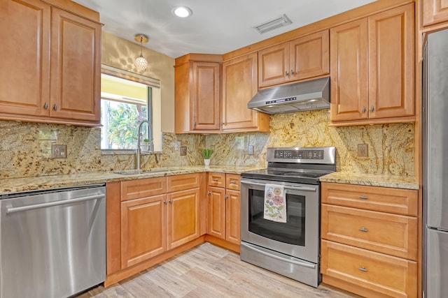 kitchen featuring sink, hanging light fixtures, light wood-type flooring, stainless steel appliances, and light stone counters