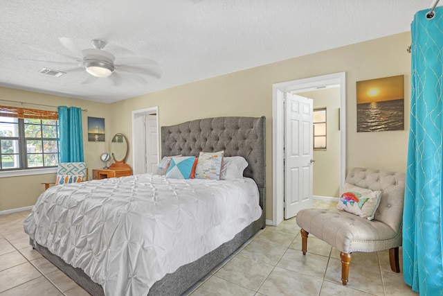 tiled bedroom with ceiling fan and a textured ceiling