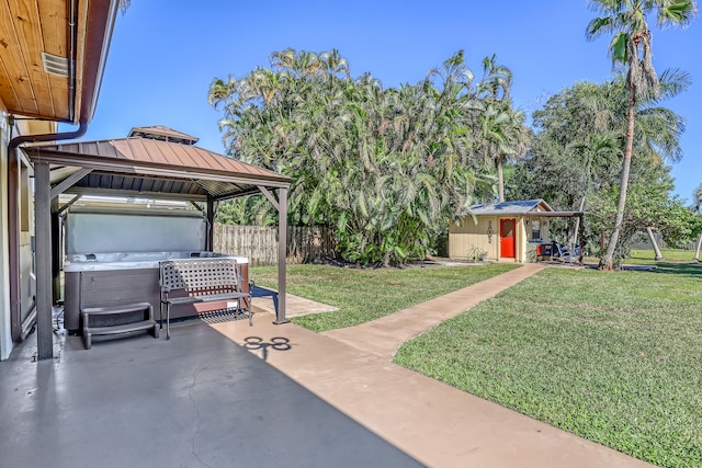 view of yard with a patio area, a gazebo, a hot tub, and a storage unit