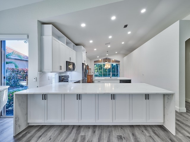 kitchen featuring kitchen peninsula, light stone counters, stainless steel appliances, white cabinetry, and lofted ceiling