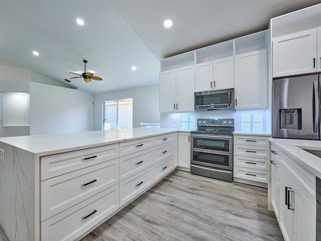 kitchen with kitchen peninsula, decorative backsplash, stainless steel appliances, white cabinets, and lofted ceiling