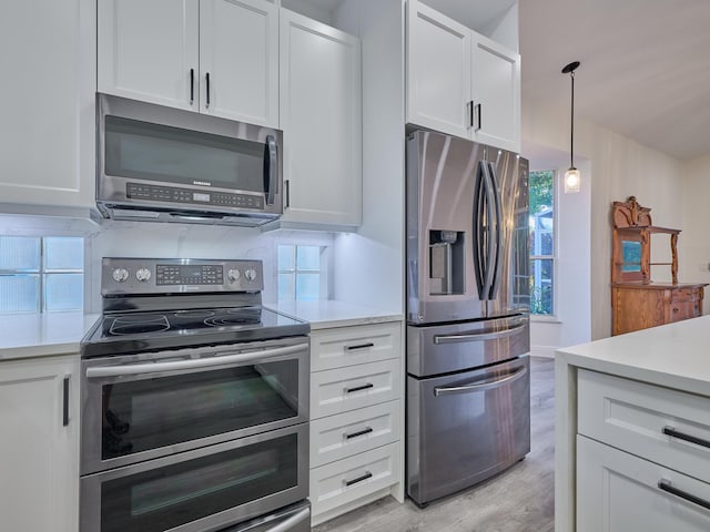 kitchen featuring white cabinets, pendant lighting, light hardwood / wood-style floors, and stainless steel appliances