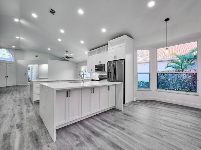 kitchen featuring ceiling fan, hanging light fixtures, stainless steel appliances, a center island with sink, and white cabinets