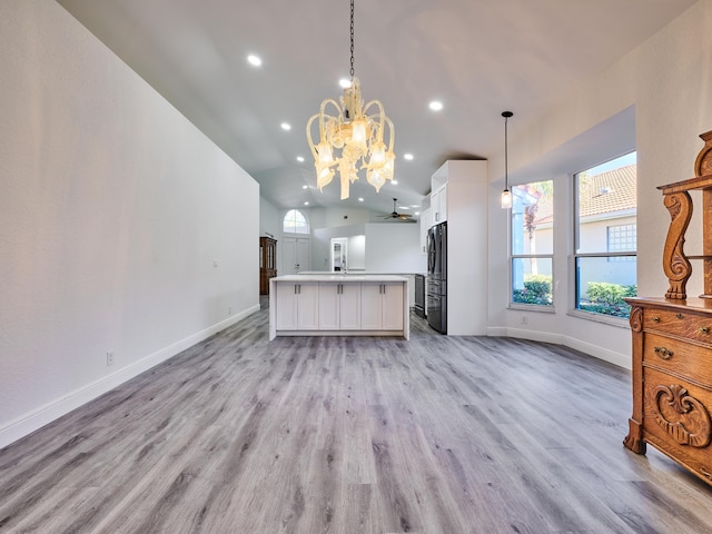 kitchen with black fridge, pendant lighting, white cabinets, light hardwood / wood-style floors, and a kitchen island