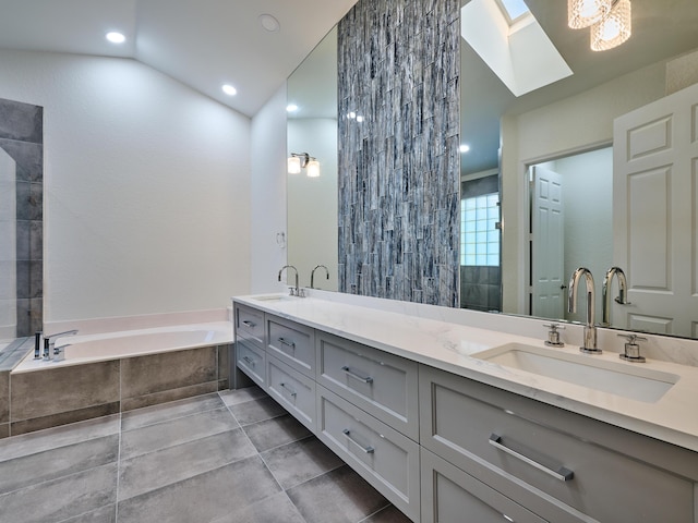 bathroom with vanity, lofted ceiling with skylight, and tiled tub