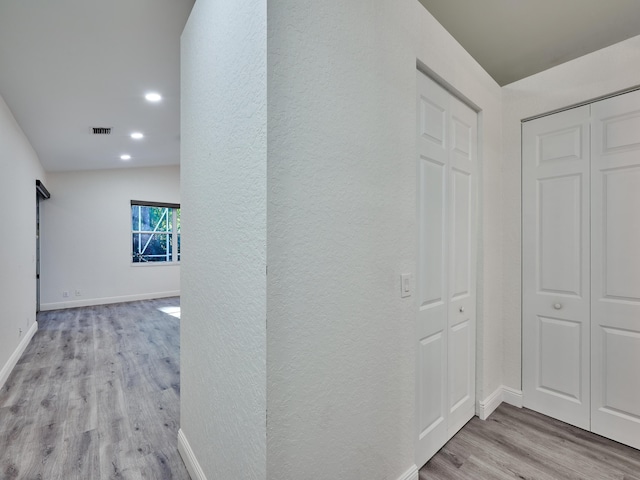 hall featuring lofted ceiling and light hardwood / wood-style flooring