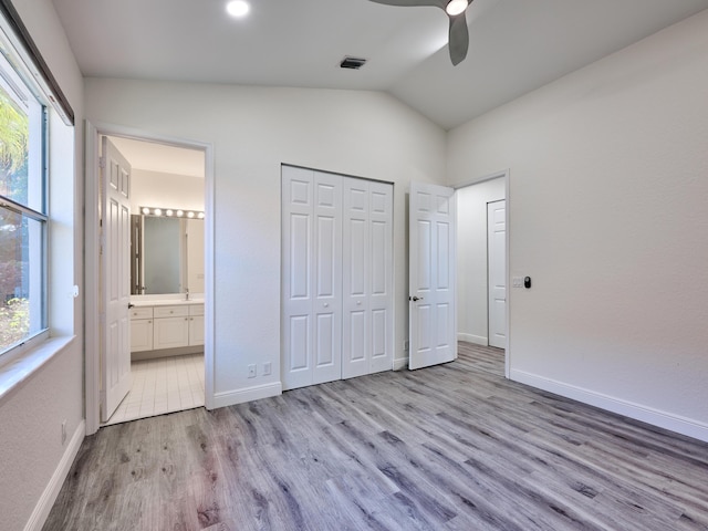 unfurnished bedroom featuring multiple windows, ceiling fan, ensuite bath, and vaulted ceiling