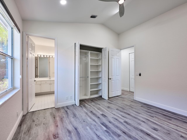 unfurnished bedroom with multiple windows, ensuite bath, vaulted ceiling, and ceiling fan