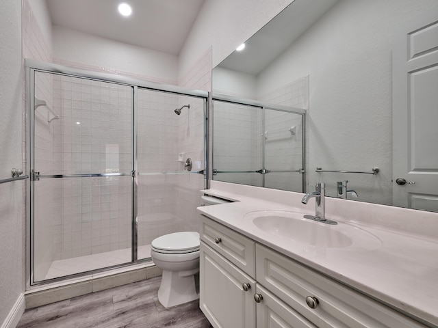 bathroom featuring hardwood / wood-style floors, vanity, a shower with door, and toilet