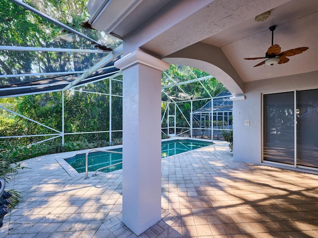 view of swimming pool with ceiling fan, a patio, and glass enclosure