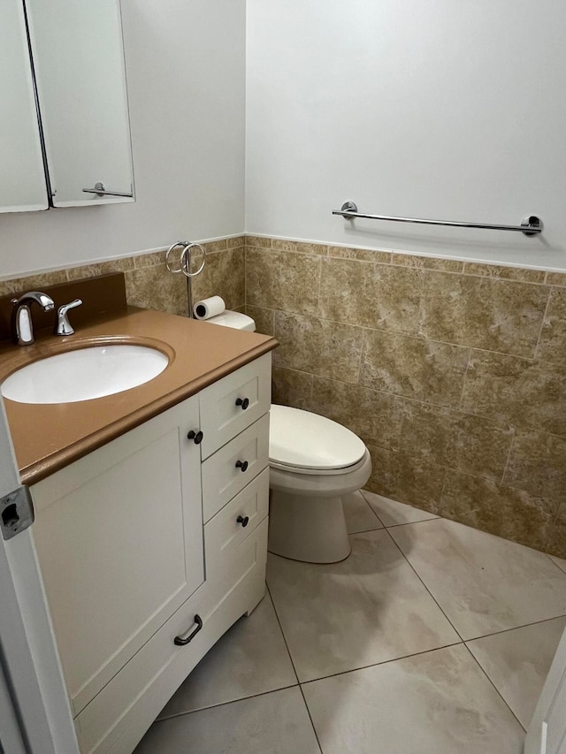 bathroom featuring tile patterned floors, vanity, tile walls, and toilet