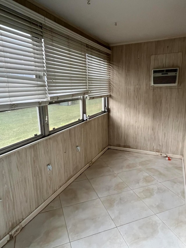 tiled spare room featuring an AC wall unit, a wealth of natural light, and wood walls