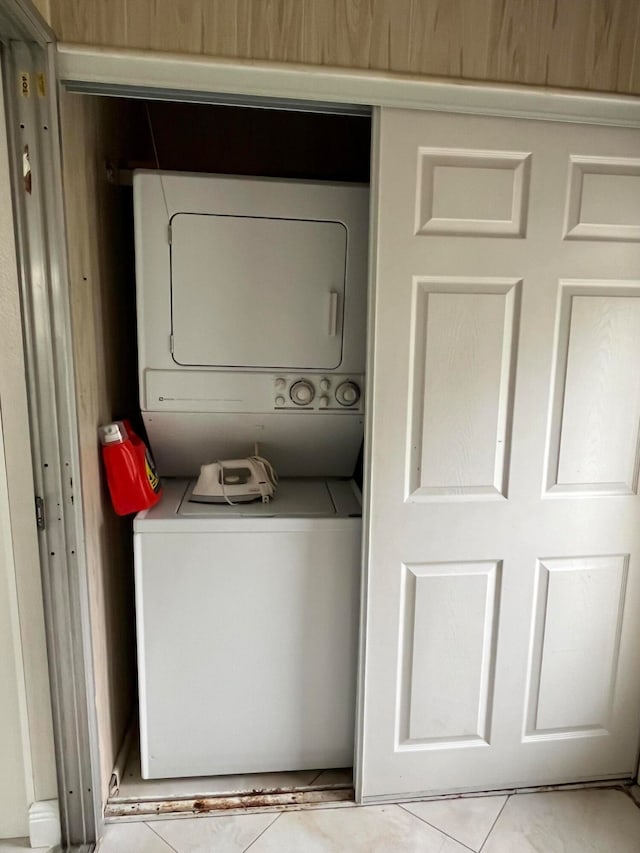 clothes washing area featuring light tile patterned floors and stacked washing maching and dryer