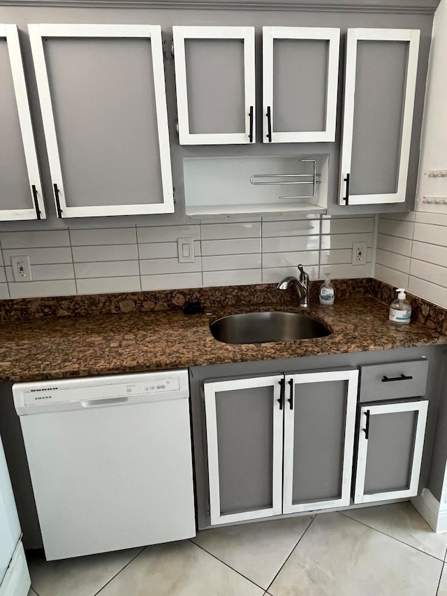 kitchen featuring tasteful backsplash, sink, white dishwasher, and light tile patterned flooring