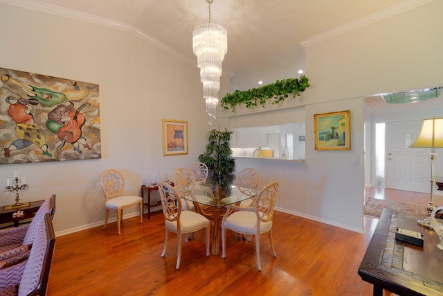 dining space with crown molding, light hardwood / wood-style flooring, a chandelier, and vaulted ceiling