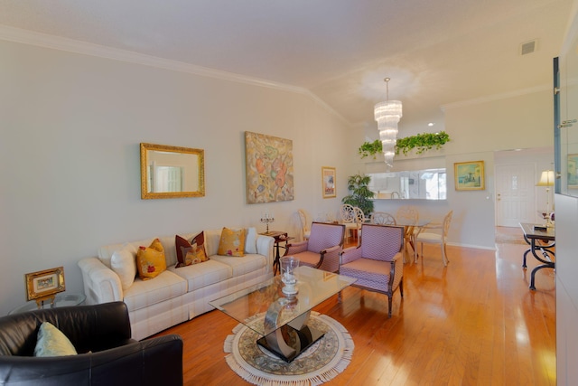 living room with hardwood / wood-style flooring, lofted ceiling, ornamental molding, and a chandelier