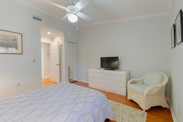 bedroom featuring a closet, ceiling fan, crown molding, and light wood-type flooring