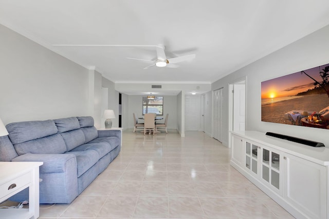 tiled living room with ceiling fan and ornamental molding