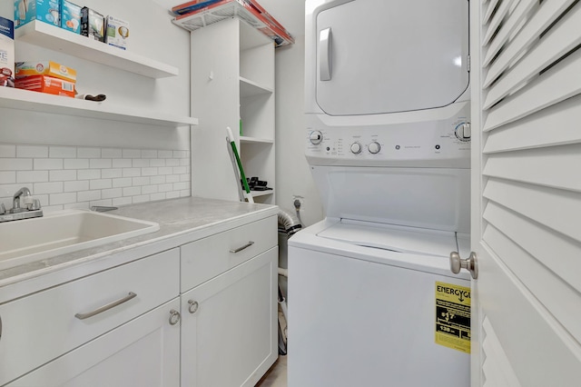 washroom with cabinets, stacked washer and clothes dryer, and sink