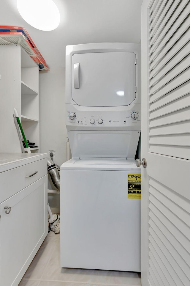 washroom with light tile patterned flooring and stacked washer and clothes dryer