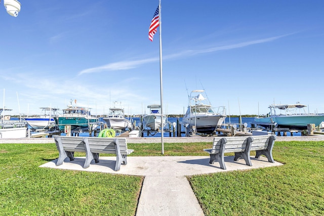 surrounding community with a dock, a yard, and a water view