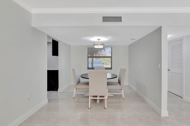 dining space featuring crown molding and light tile patterned flooring