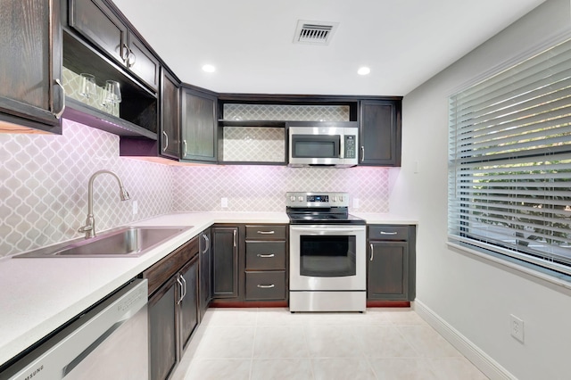 kitchen with backsplash, dark brown cabinets, stainless steel appliances, sink, and light tile patterned floors