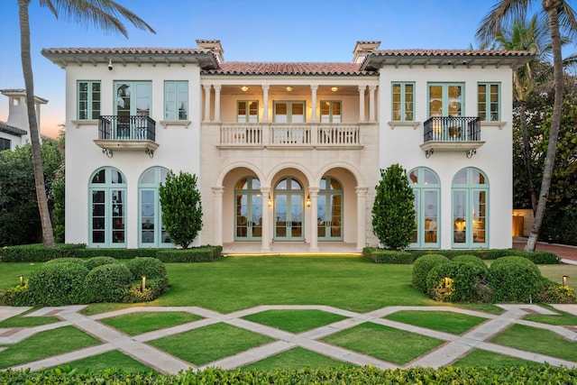 back of house with a yard, french doors, and a balcony