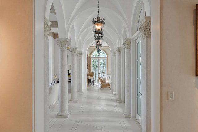 corridor featuring an inviting chandelier and ornate columns