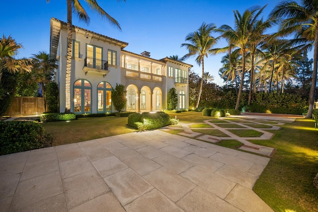 mediterranean / spanish house featuring a lawn and a balcony