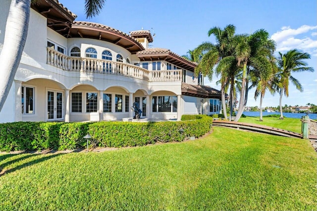 rear view of house featuring a lawn and a water view