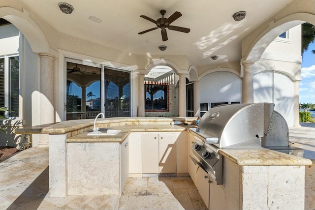 view of patio with an outdoor kitchen, ceiling fan, a grill, and sink