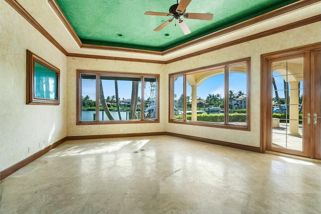 unfurnished sunroom with a tray ceiling, ceiling fan, plenty of natural light, and a water view