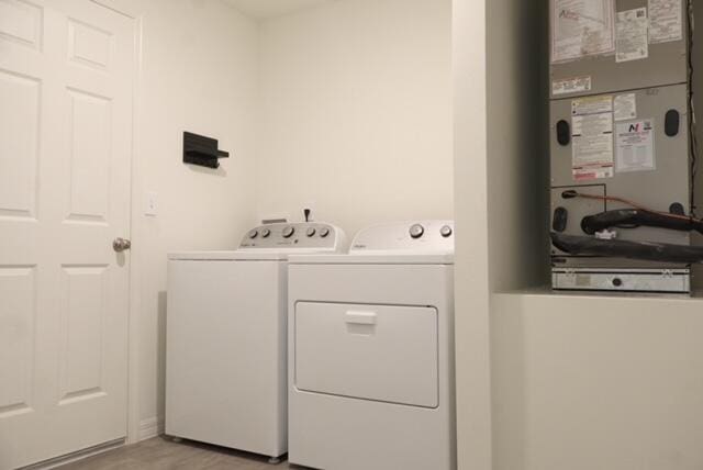 laundry room featuring washer and dryer, light hardwood / wood-style floors, and heating unit