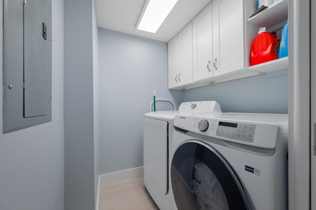 laundry area with cabinet space, washing machine and dryer, electric panel, and baseboards