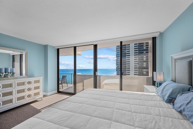 carpeted bedroom featuring access to exterior, a textured ceiling, a water view, and floor to ceiling windows