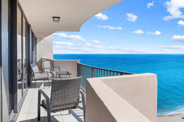 balcony featuring a view of the beach and a water view