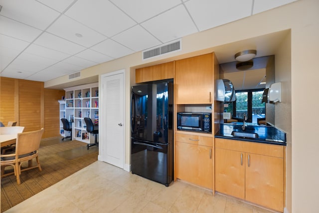 kitchen with black appliances, a paneled ceiling, light tile patterned floors, and sink