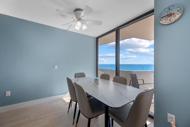 dining area featuring a water view, floor to ceiling windows, and ceiling fan