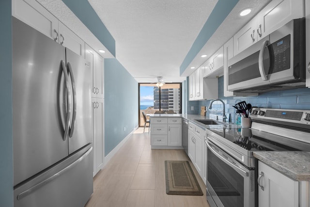 kitchen with backsplash, a textured ceiling, stainless steel appliances, sink, and white cabinets