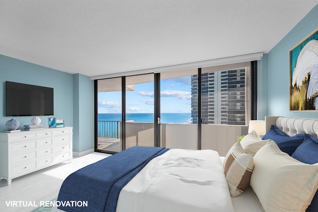 bedroom featuring a textured ceiling, light wood-style flooring, a water view, access to exterior, and floor to ceiling windows