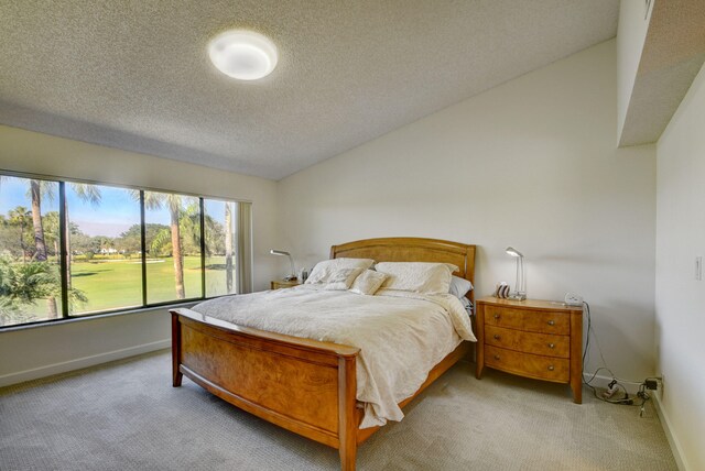 bedroom featuring a textured ceiling, light colored carpet, and lofted ceiling