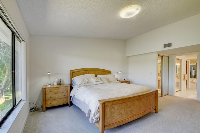 carpeted bedroom featuring ensuite bath, multiple windows, and lofted ceiling