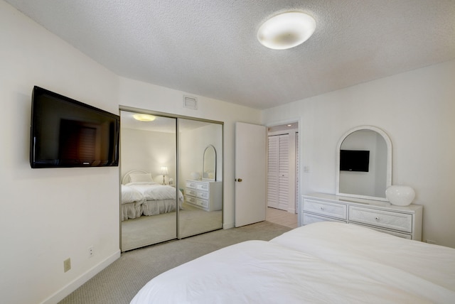 bedroom with light colored carpet and a textured ceiling