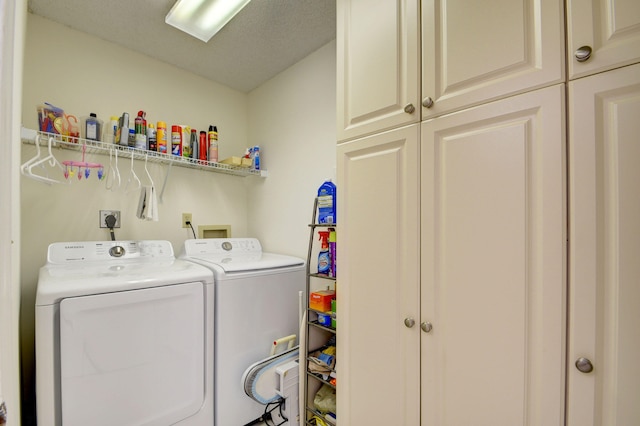 laundry room featuring washer and dryer, cabinets, and a textured ceiling